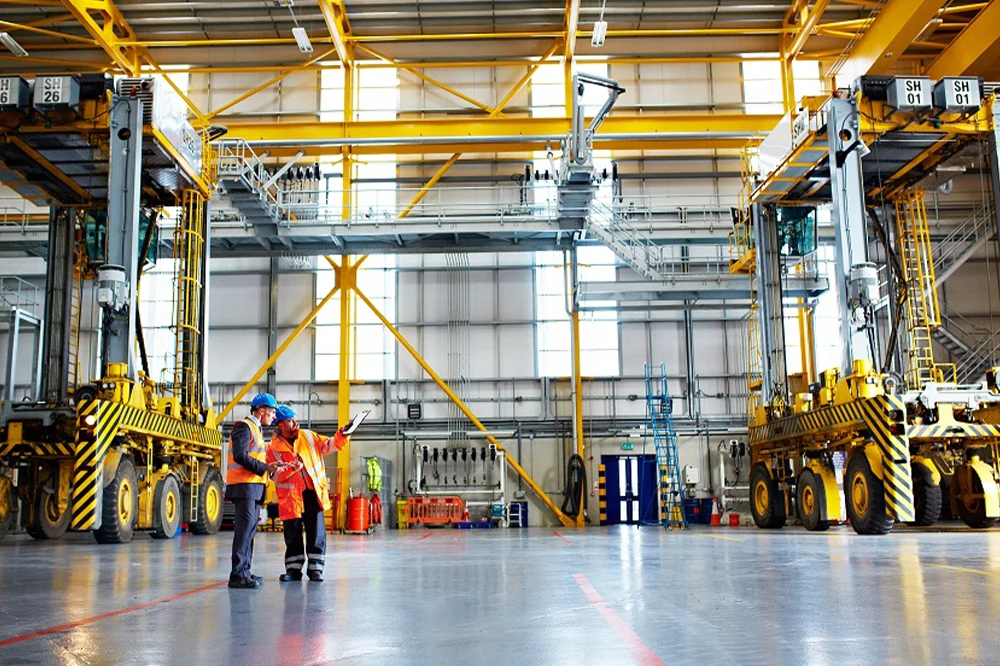 Deux techniciens discutant dans un entrepôt industriel.